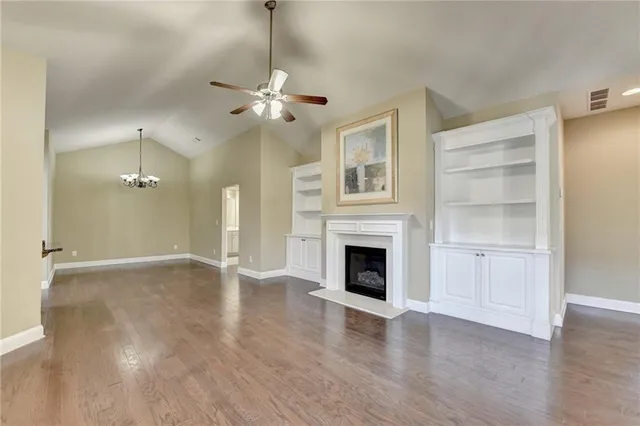 a view of an empty room with wooden floor and a fireplace