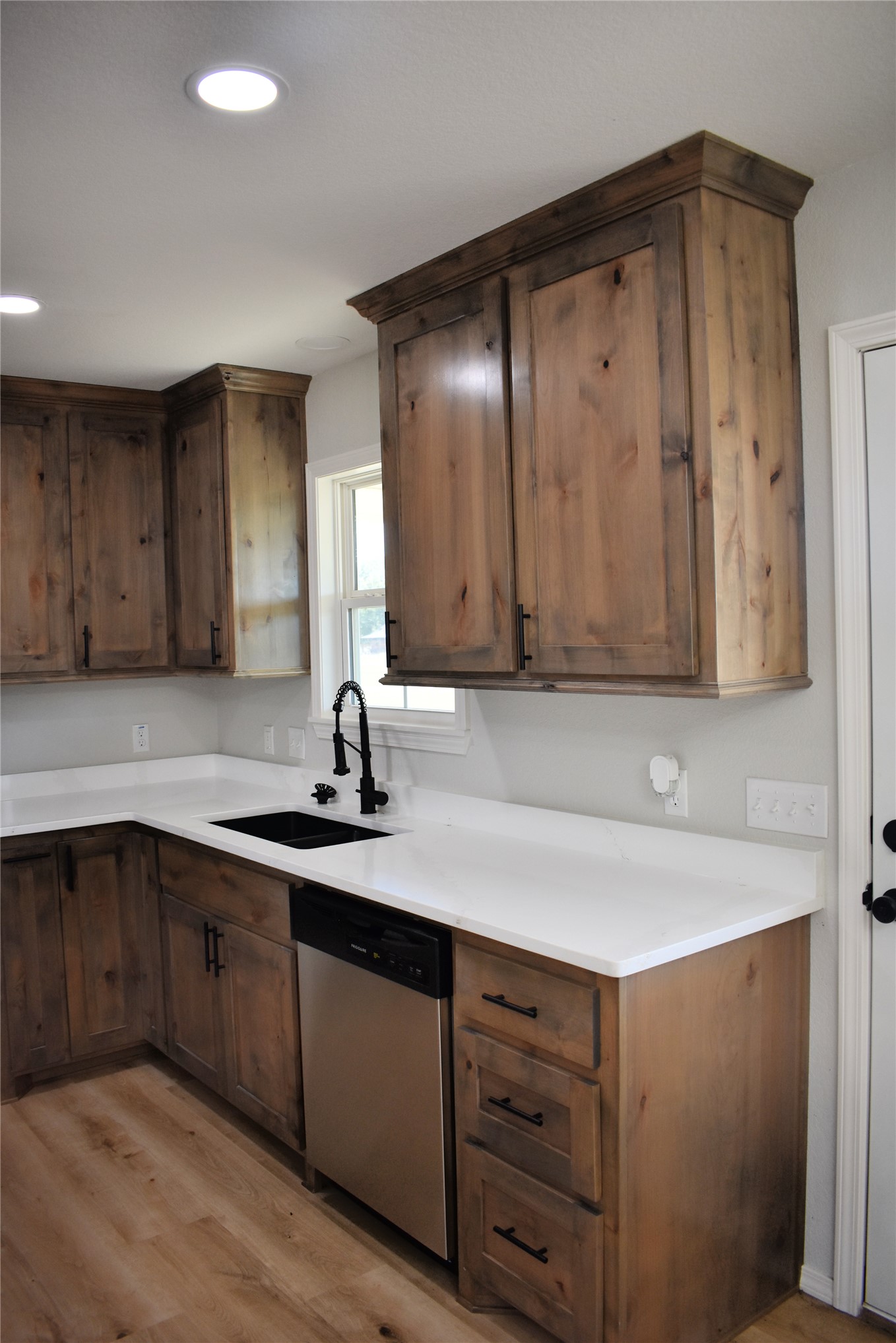 2915 East 2090 Road Hugo, OK 74743 - Photo 3 of 27 Recessed lighting illuminates the kitchen featuring wood-finish cabinetry, light-colored countertops, a stainless steel dishwasher, and a black sink with a gooseneck faucet