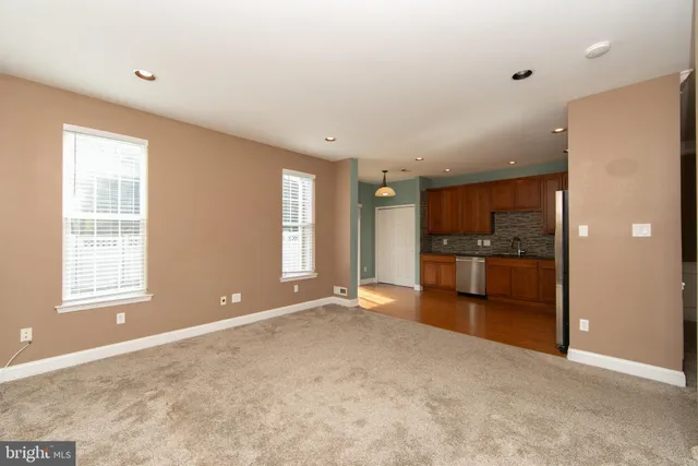 a view of empty room with kitchen and window