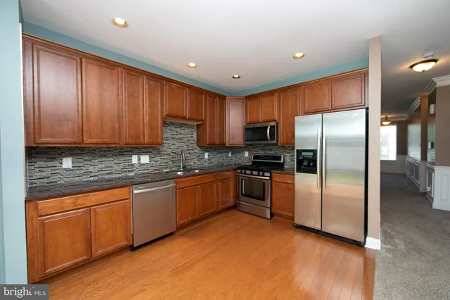 a kitchen with granite countertop stainless steel appliances a refrigerator a stove top oven and granite counter tops
