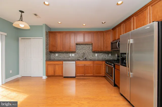 a large kitchen with stainless steel appliances granite countertop a refrigerator a sink dishwasher a stove with wooden cabinets and floor