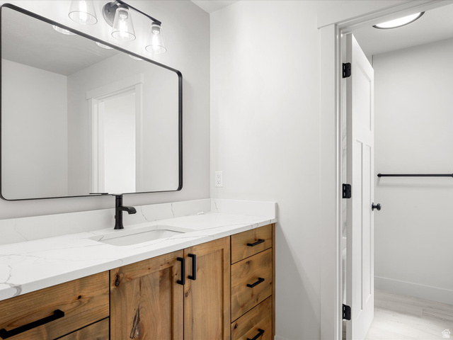 1159 North Broad Hollow Road Garden City, UT 84028 - Photo 43 of 55 Bathroom vanity featuring a wood-finish cabinet, white countertop with integrated sink, and matte black hardware