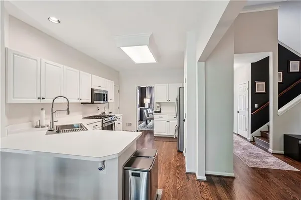 a kitchen with stainless steel appliances a sink dishwasher a refrigerator and a dining table with wooden floor