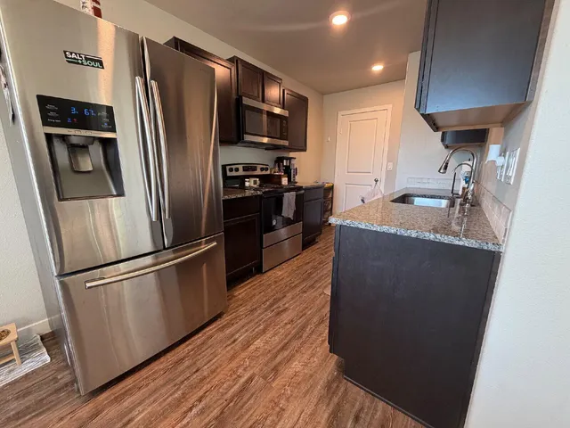a kitchen with granite countertop a refrigerator stove and oven