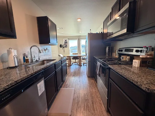 a kitchen with stainless steel appliances granite countertop a sink stove and refrigerator
