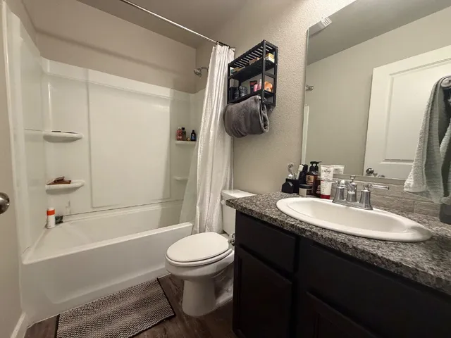 a bathroom with a granite countertop sink toilet and shower