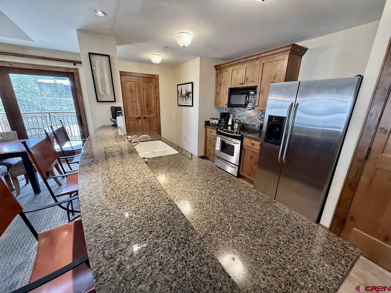 620 Gothic Road, Unit 206 Crested Butte, CO 81225 - Photo 13 of 41 a kitchen with stainless steel appliances granite countertop a refrigerator stove top oven dining table and chairs