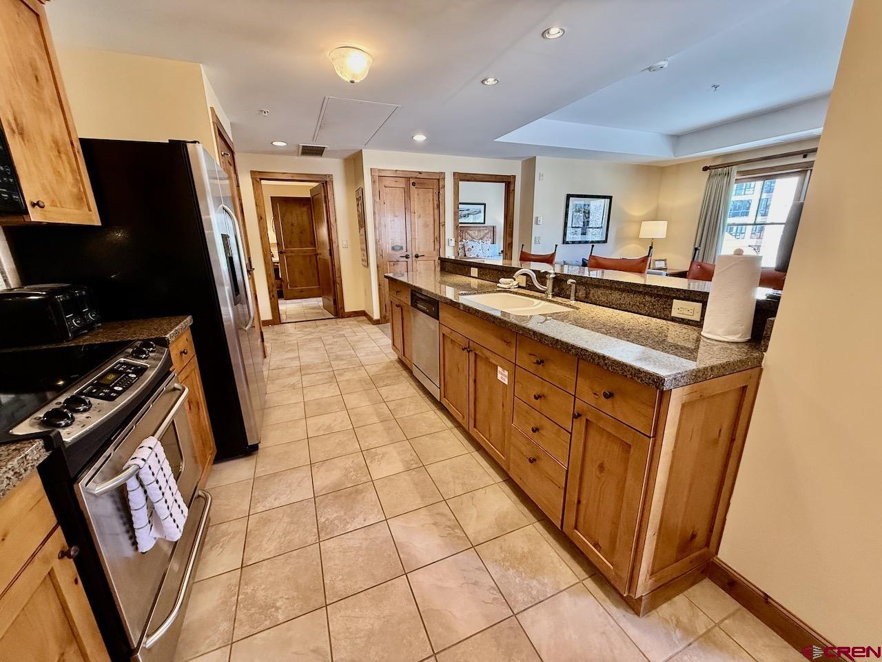 620 Gothic Road, Unit 206 Crested Butte, CO 81225 - Photo 16 of 41 a large kitchen with stainless steel appliances granite countertop a large stove top oven a sink a dining table and chairs