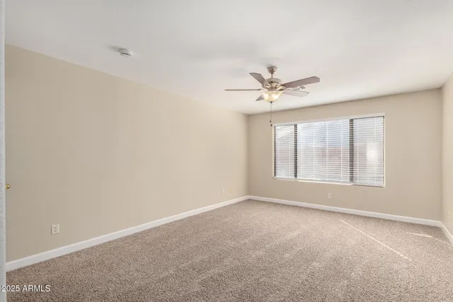 an empty room with windows and ceiling fan