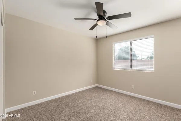 an empty room with a window and a fan