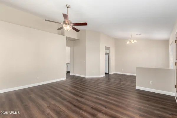 a view of an empty room with wooden floor and a ceiling fan