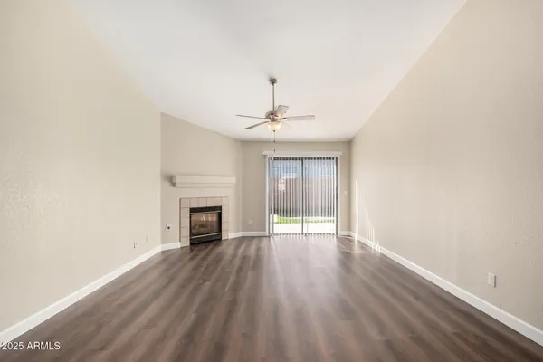 an empty room with wooden floor fireplace and windows