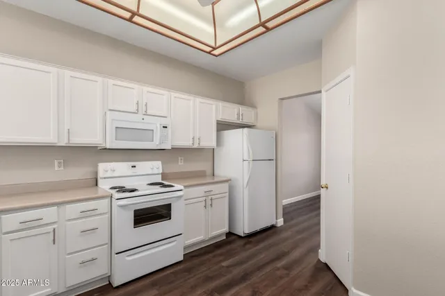 a kitchen with cabinets appliances wooden floor and view living room