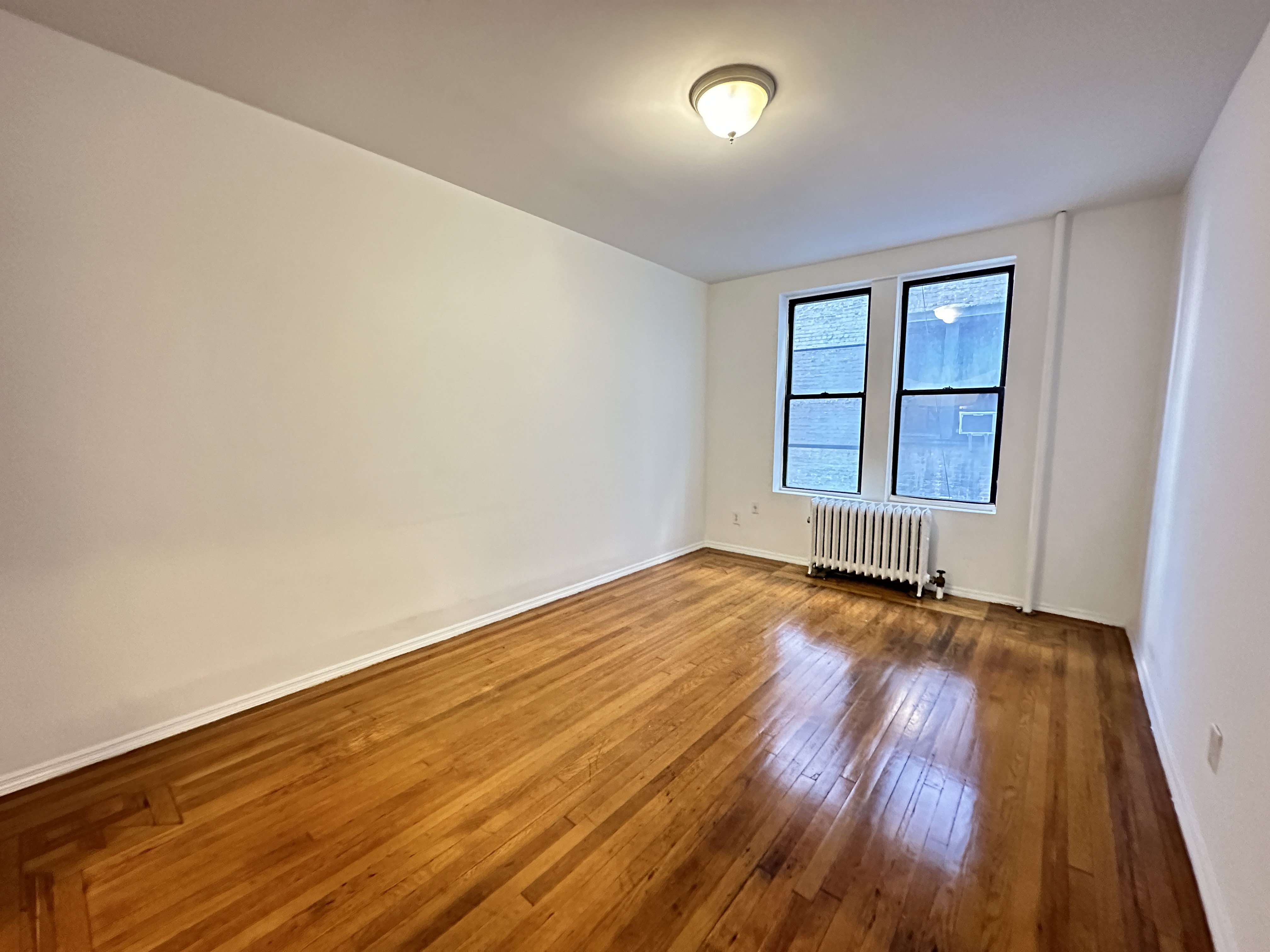 601 West 149th Street, Unit 35 Manhattan, NY 10031 - Photo 6 of 9 an empty room with wooden floor and windows