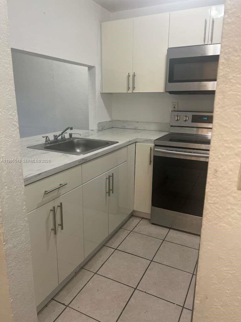 4550 Northwest 9th Street, Unit 114E Miami, FL 33126 - Photo 2 of 9 a kitchen with a sink stove and cabinets