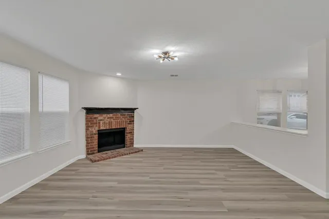 a view of empty room with wooden floor and fireplace