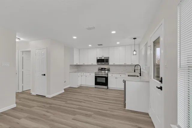 a large white kitchen with stainless steel appliances granite countertop a stove and a refrigerator