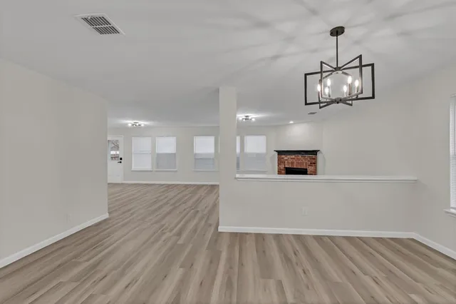 a view of an empty room with wooden floor and chandelier