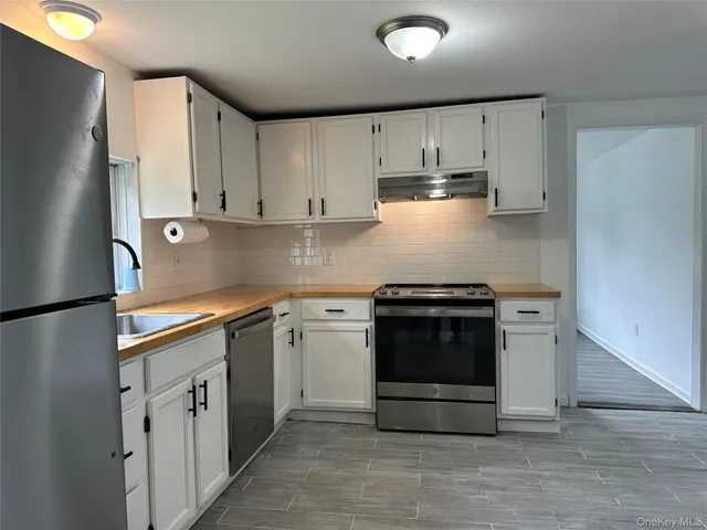 a kitchen with stainless steel appliances granite countertop a stove a refrigerator and a white cabinets