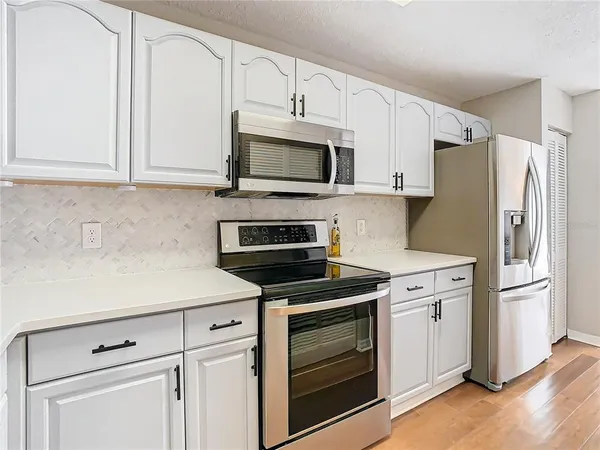 a kitchen with cabinets stainless steel appliances and wooden floor