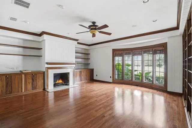a view of an empty room with wooden floor fireplace and a window