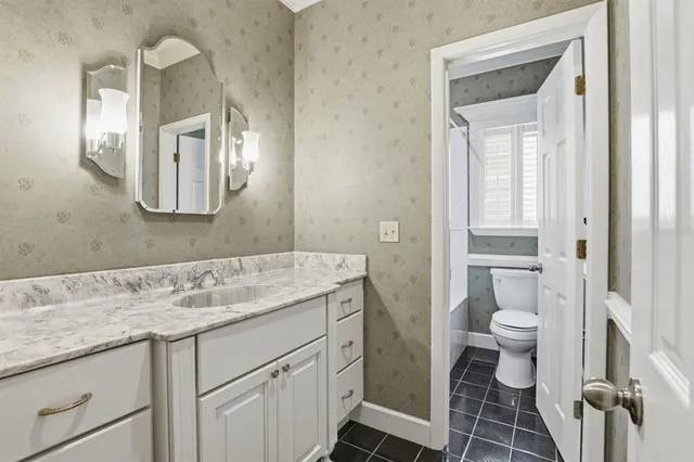 a bathroom with a granite countertop sink a toilet and a mirror