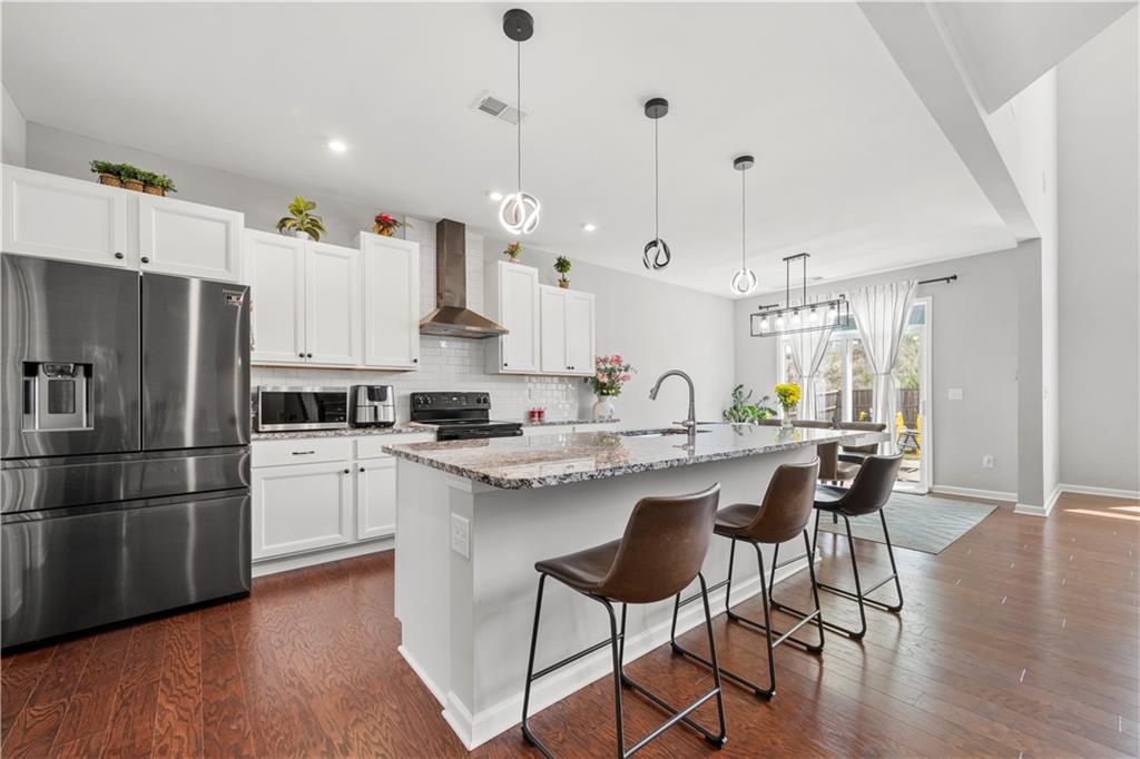 4607 Underwood Walk Powder Springs, GA 30127 - Photo 6 of 31 a kitchen with stainless steel appliances granite countertop a sink a stove a refrigerator and island with wooden floor