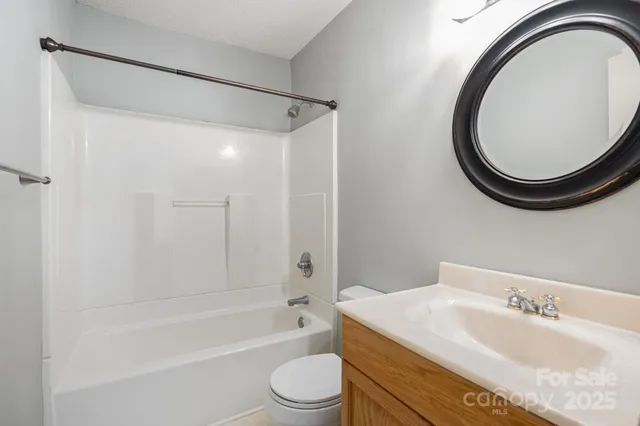 a bathroom with a granite countertop sink toilet a mirror and a bathtub
