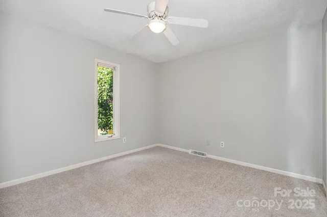 an empty room with a window and a fan