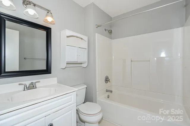 a bathroom with a granite countertop sink a toilet a mirror a vanity and shower