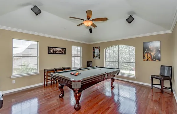 a living room with furniture pool table wooden floor and a ceiling fan