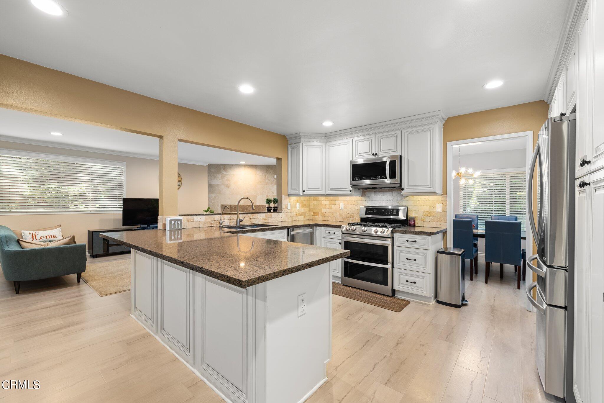 9356 Skyview Terrace Tujunga, CA 91042 - Photo 13 of 39 a kitchen with stainless steel appliances granite countertop a stove top oven a sink dishwasher a dining table and chairs with wooden floor