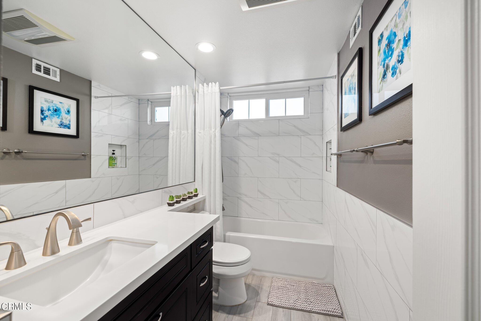 9356 Skyview Terrace Tujunga, CA 91042 - Photo 27 of 39 a bathroom with a granite countertop sink toilet a mirror a vanity and shower