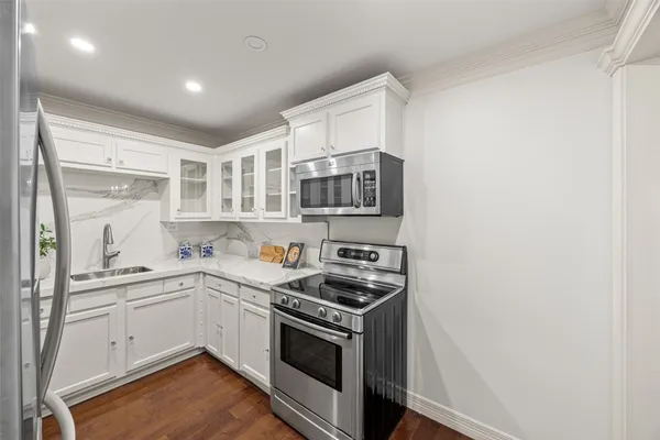 a kitchen with stainless steel appliances granite countertop a sink and a stove top oven with wooden floor