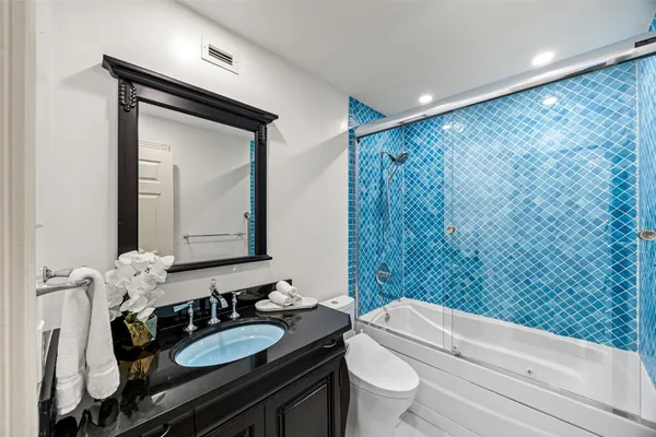 a bathroom with a granite countertop sink mirror vanity and toilet