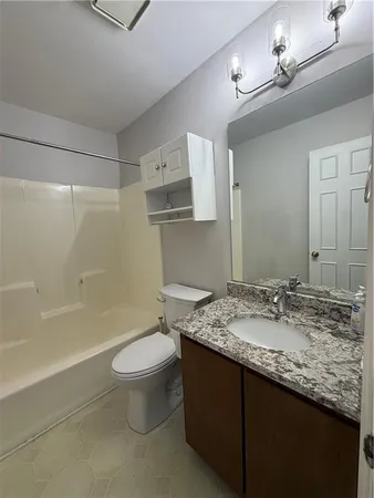 a bathroom with a granite countertop sink a toilet a mirror and bathtub