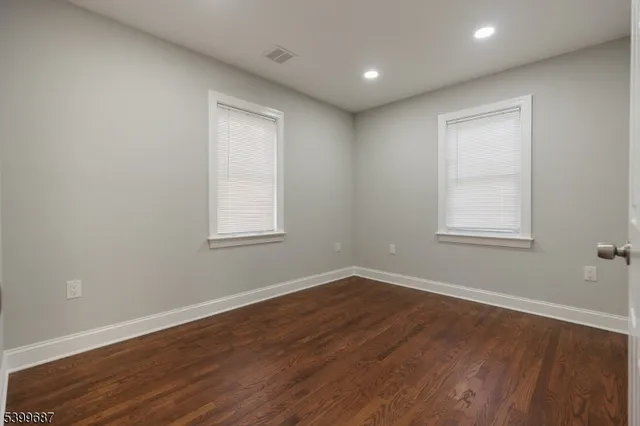 a view of a big room with wooden floor and windows