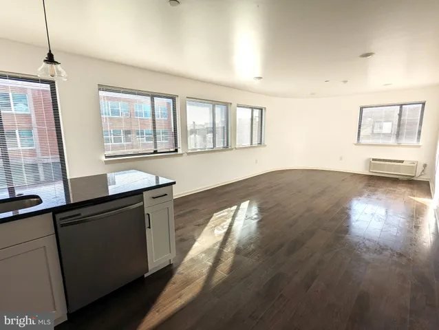 a open kitchen with granite countertop a refrigerator a sink dishwasher a stove and white countertops with wooden floor