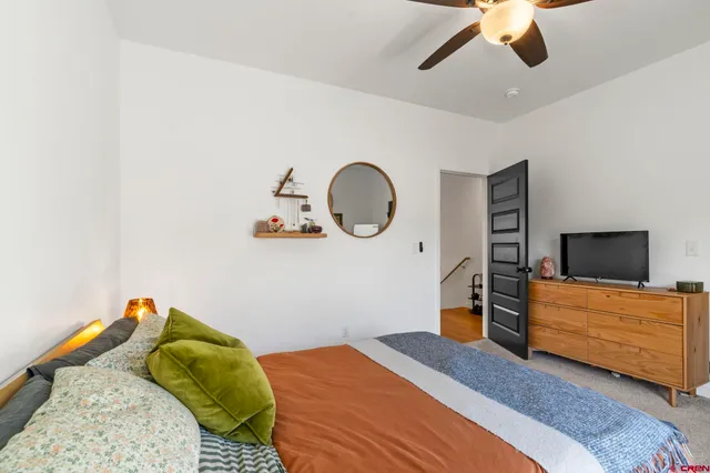 a bedroom with a bed a flat tv screen and dresser