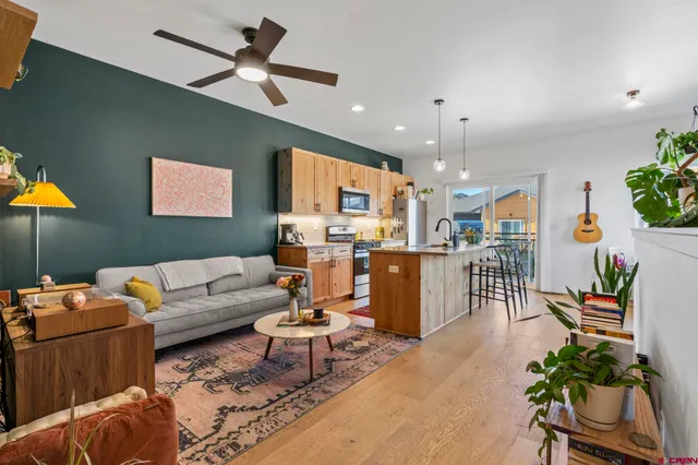 a living room with furniture kitchen view and a chandelier