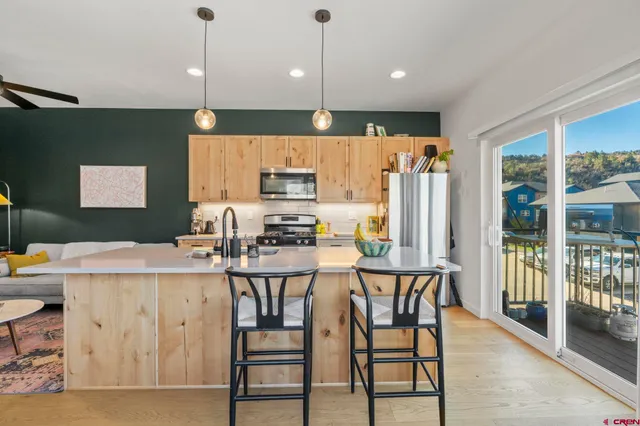 a kitchen with stainless steel appliances kitchen island granite countertop a refrigerator a stove a sink a dining table and chairs with wooden floor
