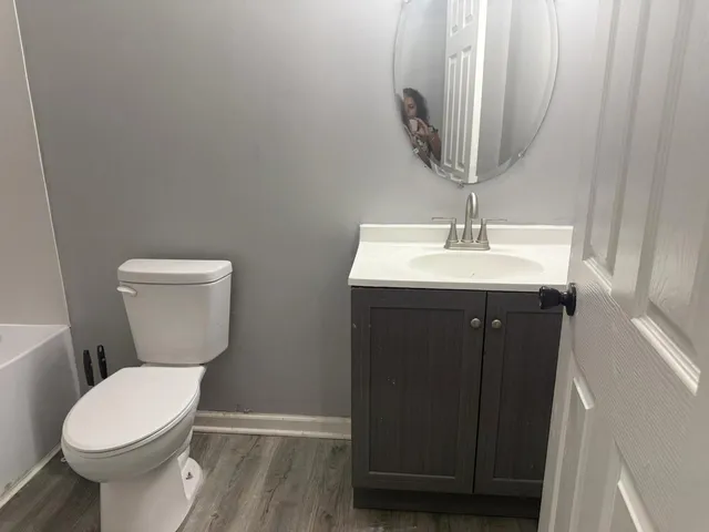 a bathroom with a toilet a sink and wooden floor