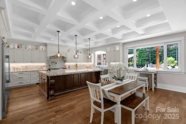 a dining hall with stainless steel appliances kitchen island granite countertop a table chairs and a large window