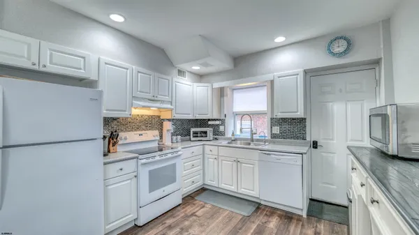 a kitchen with white cabinets and white appliances