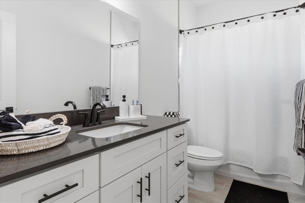 1054 Southwest 67th Street Gainesville, FL 32607 - Photo 23 of 37 a bathroom with a granite countertop sink mirror vanity and toilet