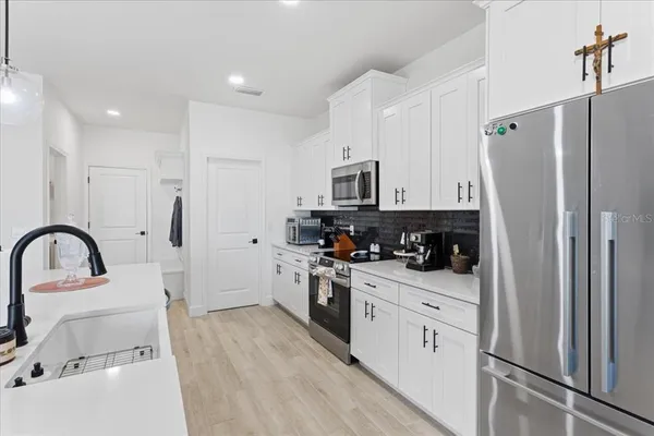 a kitchen with stainless steel appliances kitchen island a refrigerator sink and white cabinets