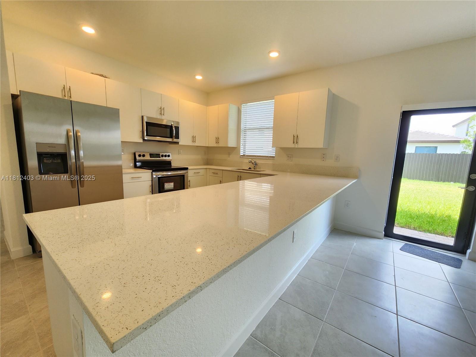 12959 Southwest 229th Lane Miami, FL 33170 - Photo 7 of 28 a large kitchen with kitchen island a sink a counter top space cabinets and stainless steel appliances