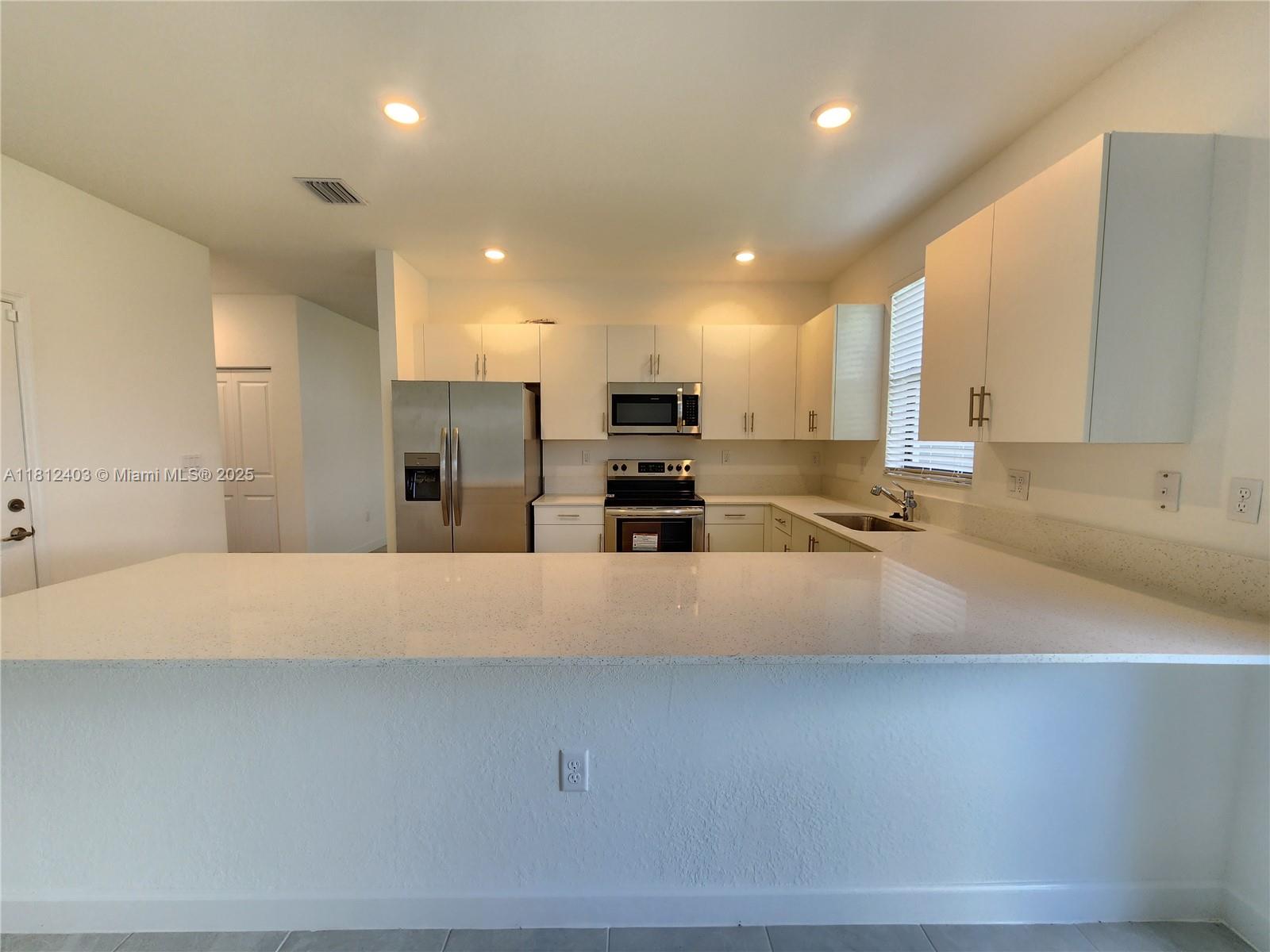 12959 Southwest 229th Lane Miami, FL 33170 - Photo 8 of 28 a large kitchen with kitchen island a sink stainless steel appliances and cabinets