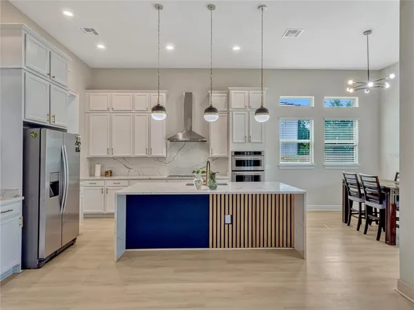 a kitchen with stainless steel appliances granite countertop a refrigerator a sink dishwasher a stove and white cabinets with wooden floor