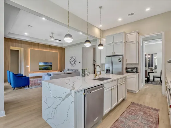 a large kitchen with kitchen island a large counter top space a sink stainless steel appliances and cabinets